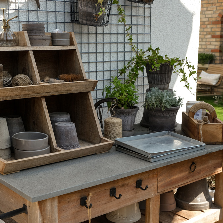 Holztisch im Garten mit Pflanzwerkzeugen und Tontöpfen in natürlichen Farben, Gartendekoration