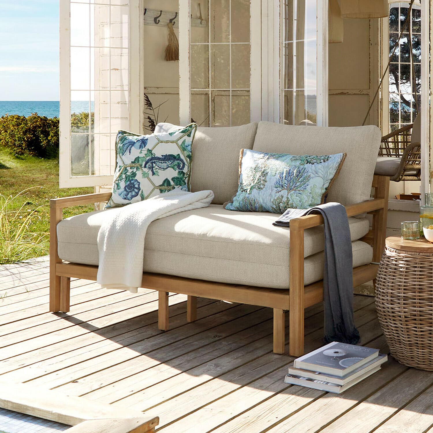 Ausziehsofa Tjorna Beiges Sofa mit Holzrahmen auf Terrasse mit Garten- und Meerblick, dekoratives Kissen
