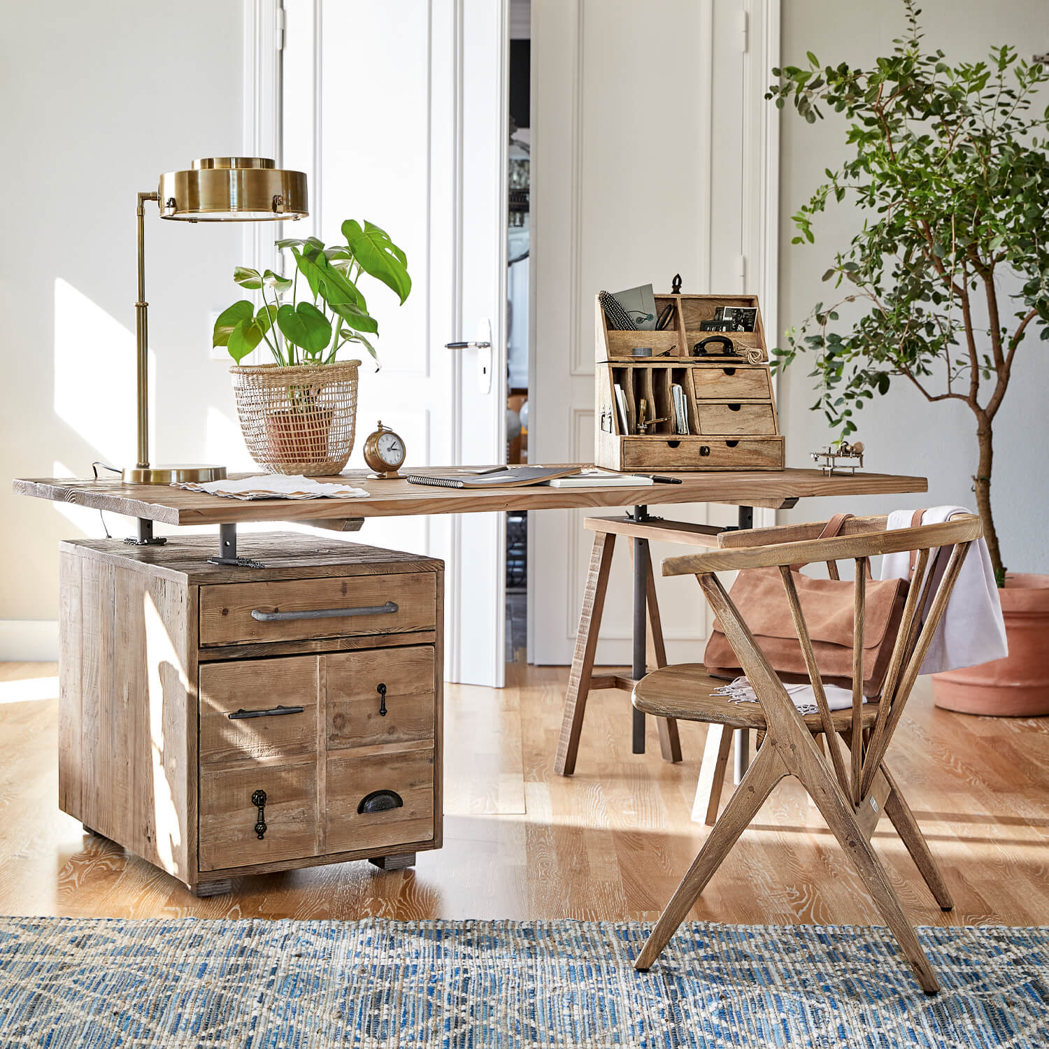 Holzschreibtisch mit Schubladen und Metallgriffen, goldene Lampe und Pflanze im Korb