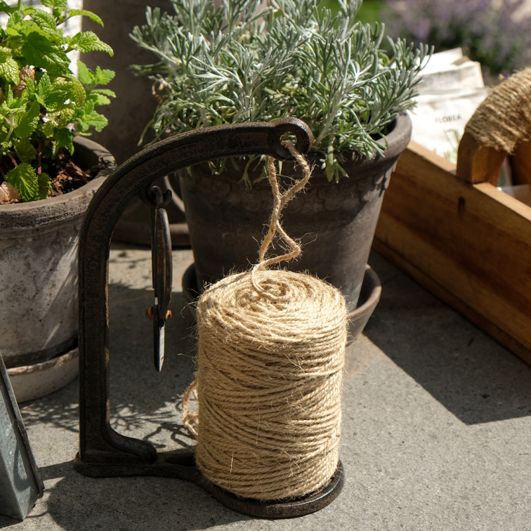 Natürliche Juteschnur auf Metallhalter neben Kräutertöpfen für Gartenarbeit und Dekoration