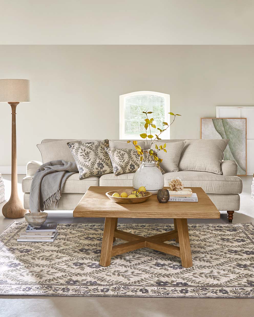 Beige Sofa mit Kissen und Holztisch auf gemustertem Teppich in gemütlichem Wohnzimmer