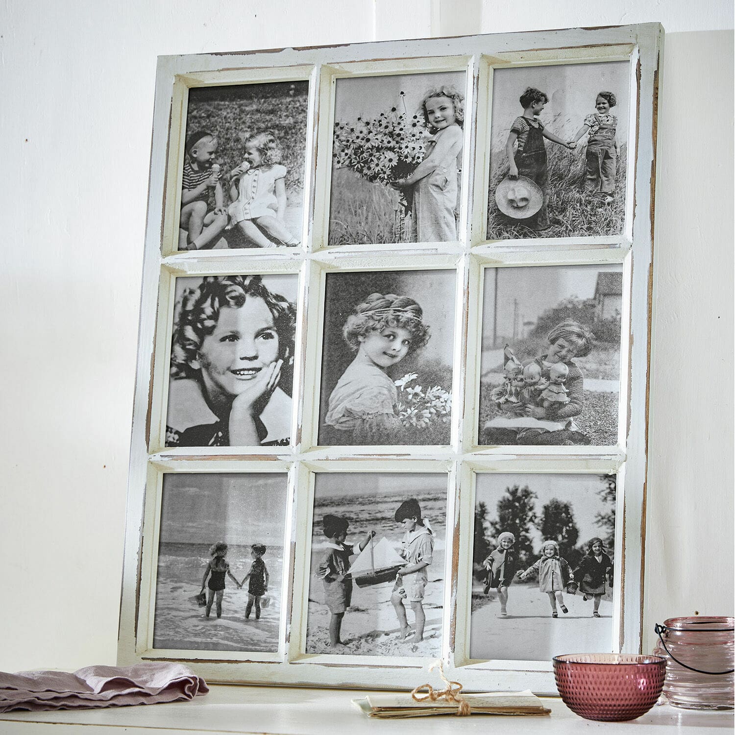 Bilderrahmen Vira Weißer Holzrahmen mit neun schwarz-weißen Vintage-Kinderfotos auf einem Tisch