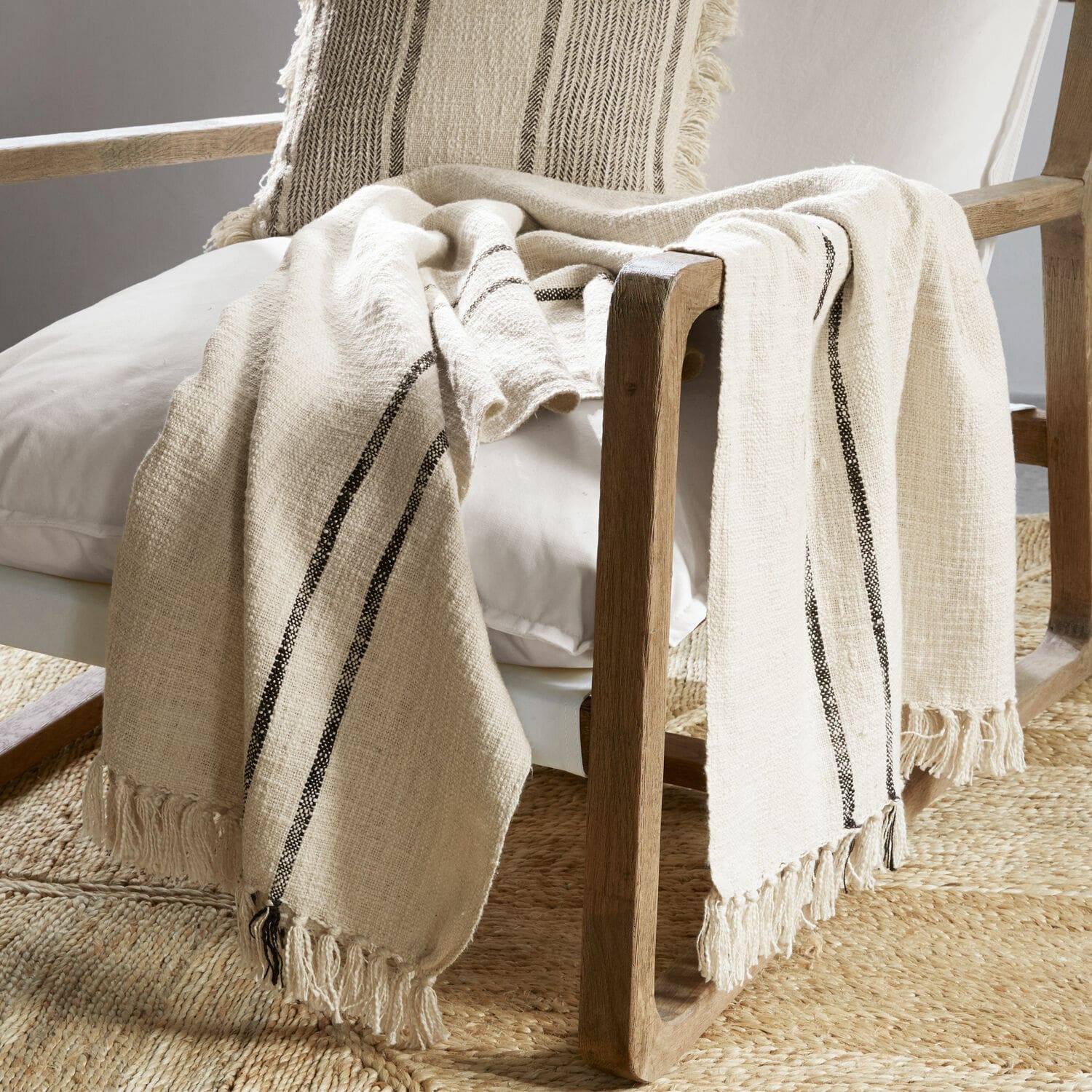 Plaid Toos Beiges Baumwollplaid mit schwarzen Streifen und Fransen auf Holzstuhl im Wohnzimmer