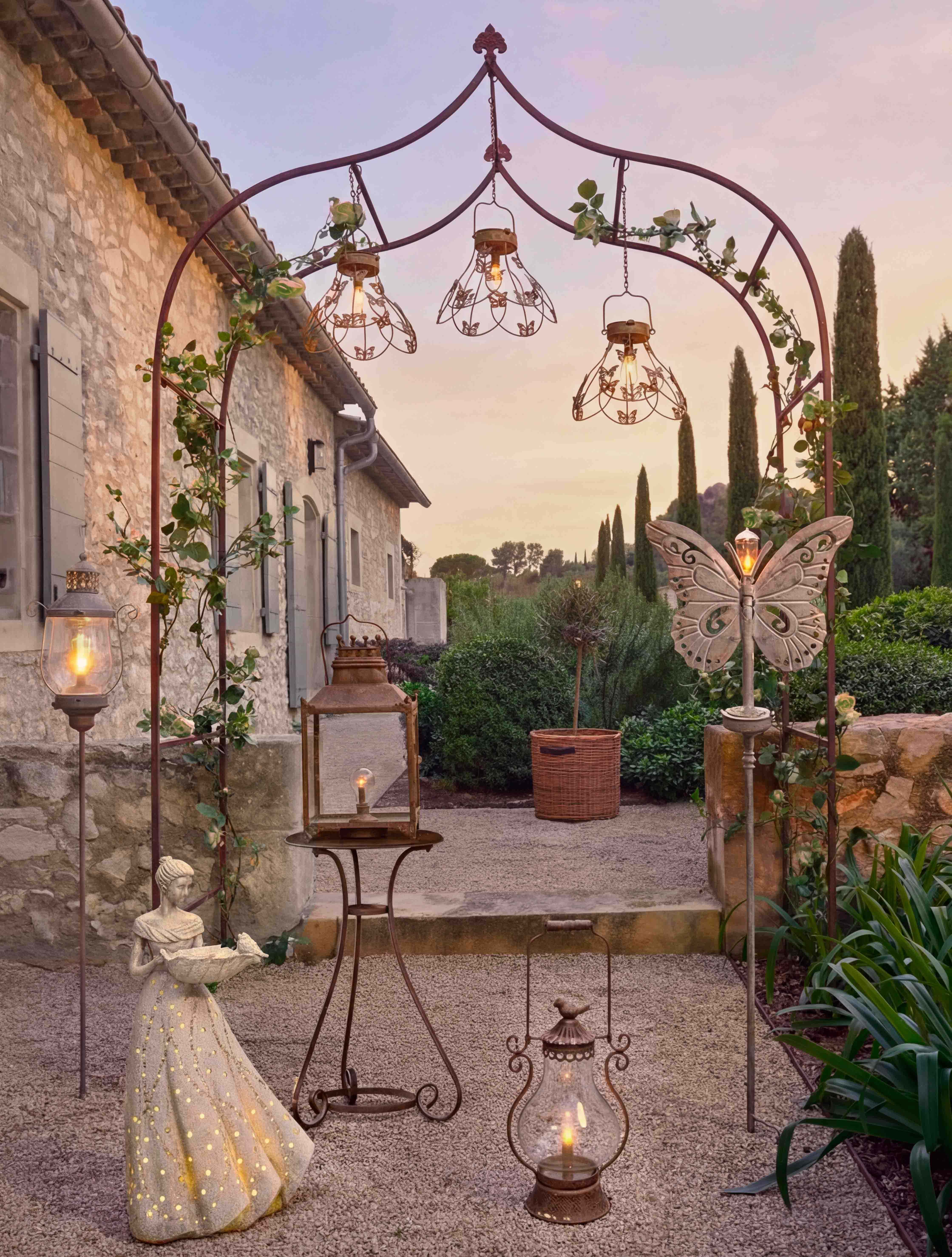 Dekorativer Metallbogen mit Laternen und Frauenfigur im Garten bei warmem Abendlicht