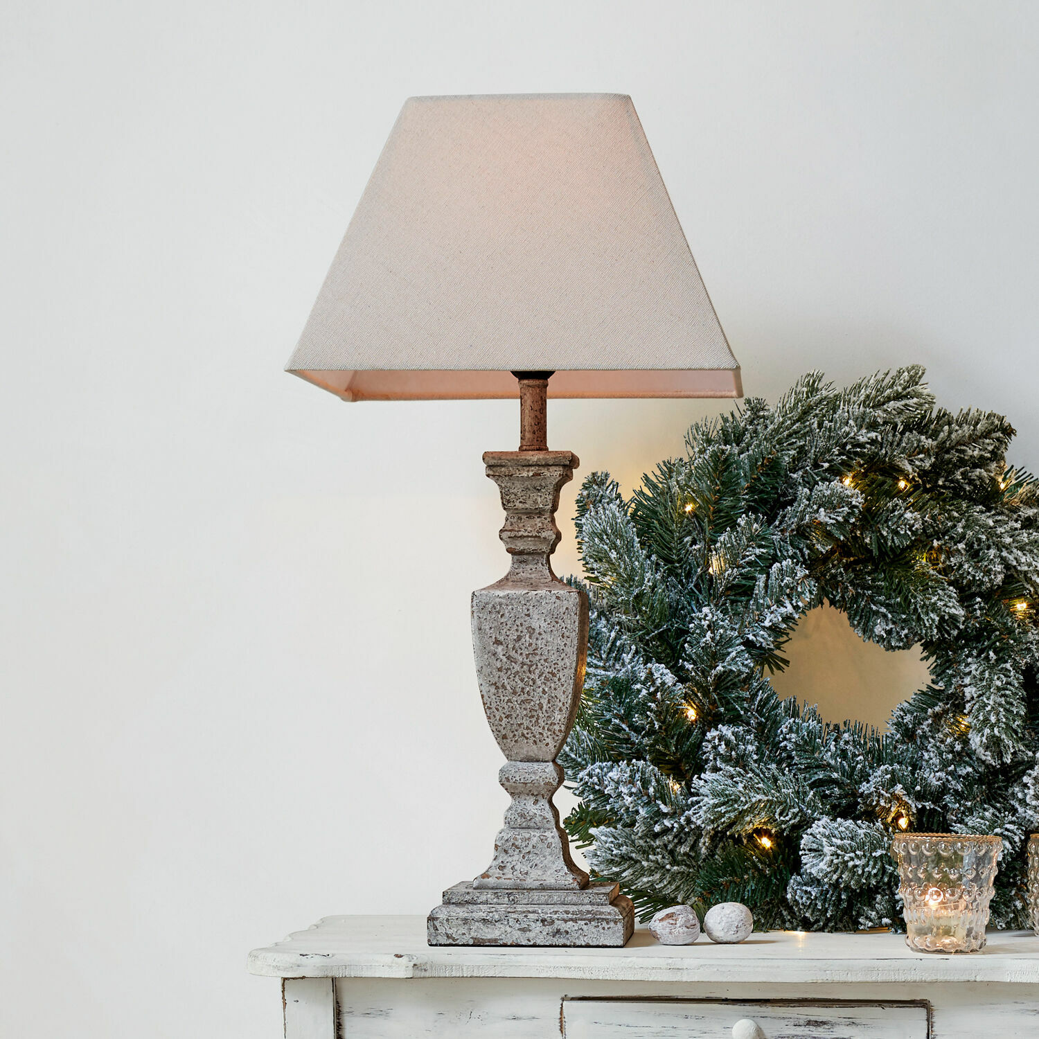 Tischlampe Gorham Beige Steintischlampe mit Lampenschirm neben grünem Weihnachtskranz mit Lichterkette auf weissem Tisch