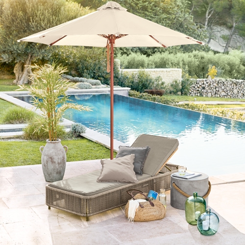 Gartenliege mit beigem Polster und Sonnenschirm beim Pool, Dekoration aus Rattan und Glas