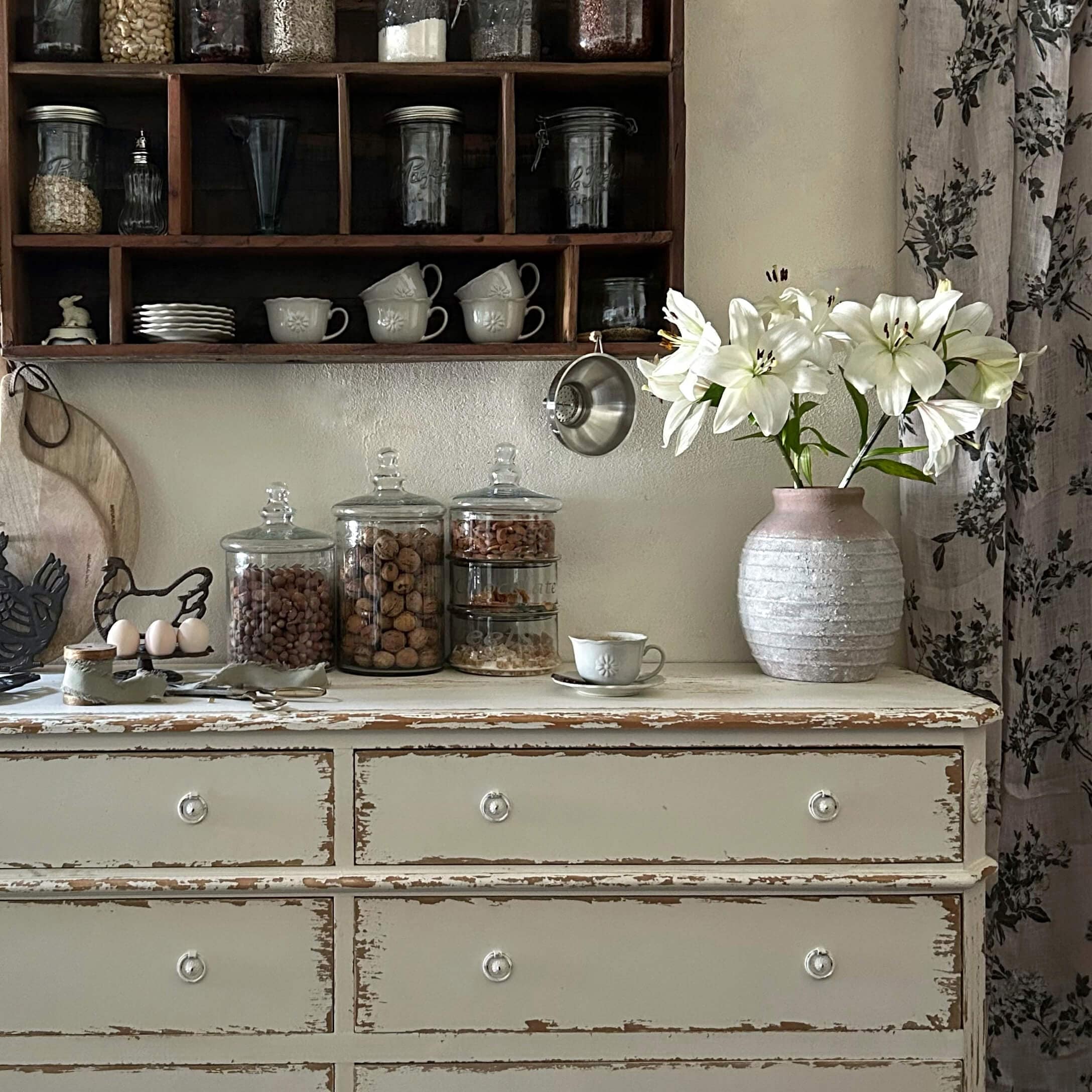 Rustikaler weisser Schrank mit rosa Keramikvase und weissen Lilien in Vintage-Küche