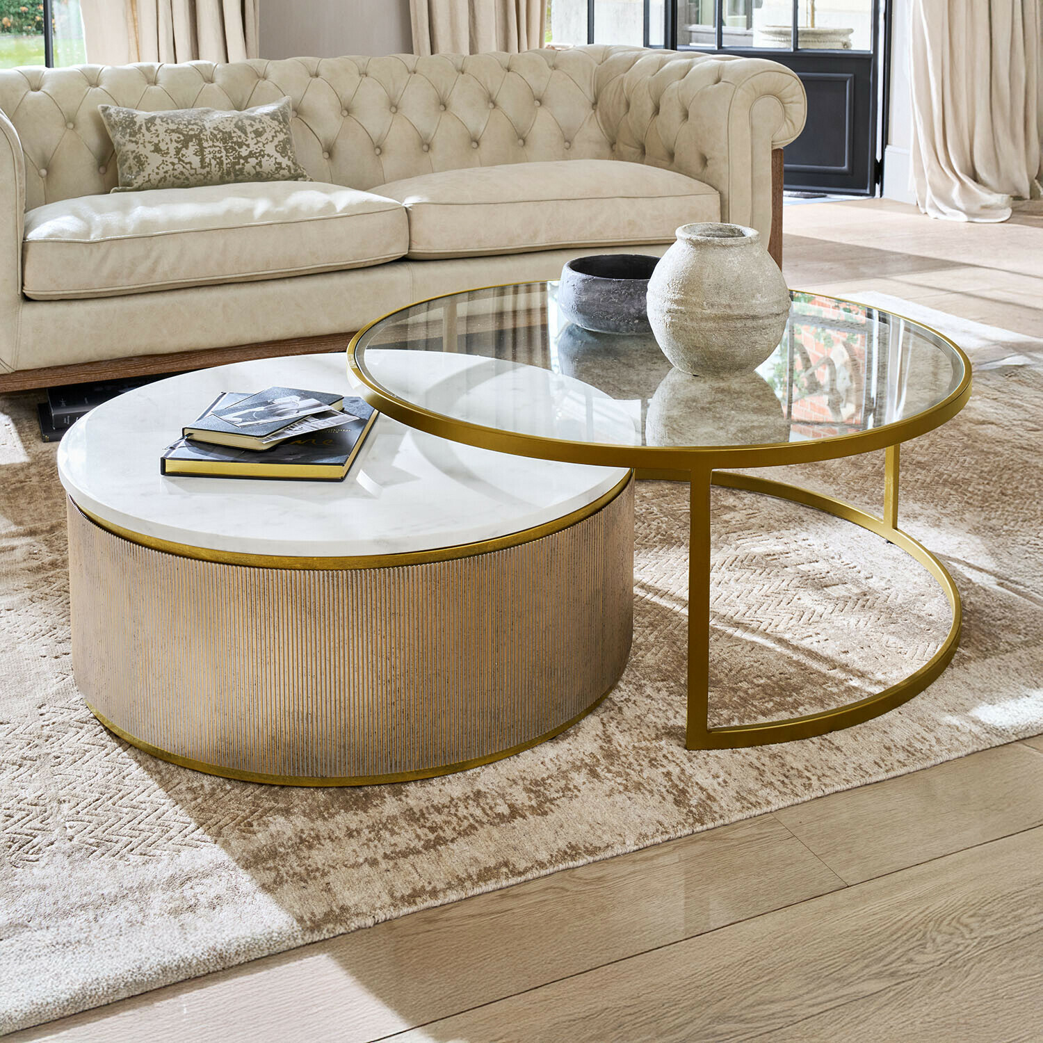 Zweier-Set Couchtische mit Marmor- und Glasplatte sowie goldfarbenem Gestell im Wohnzimmer