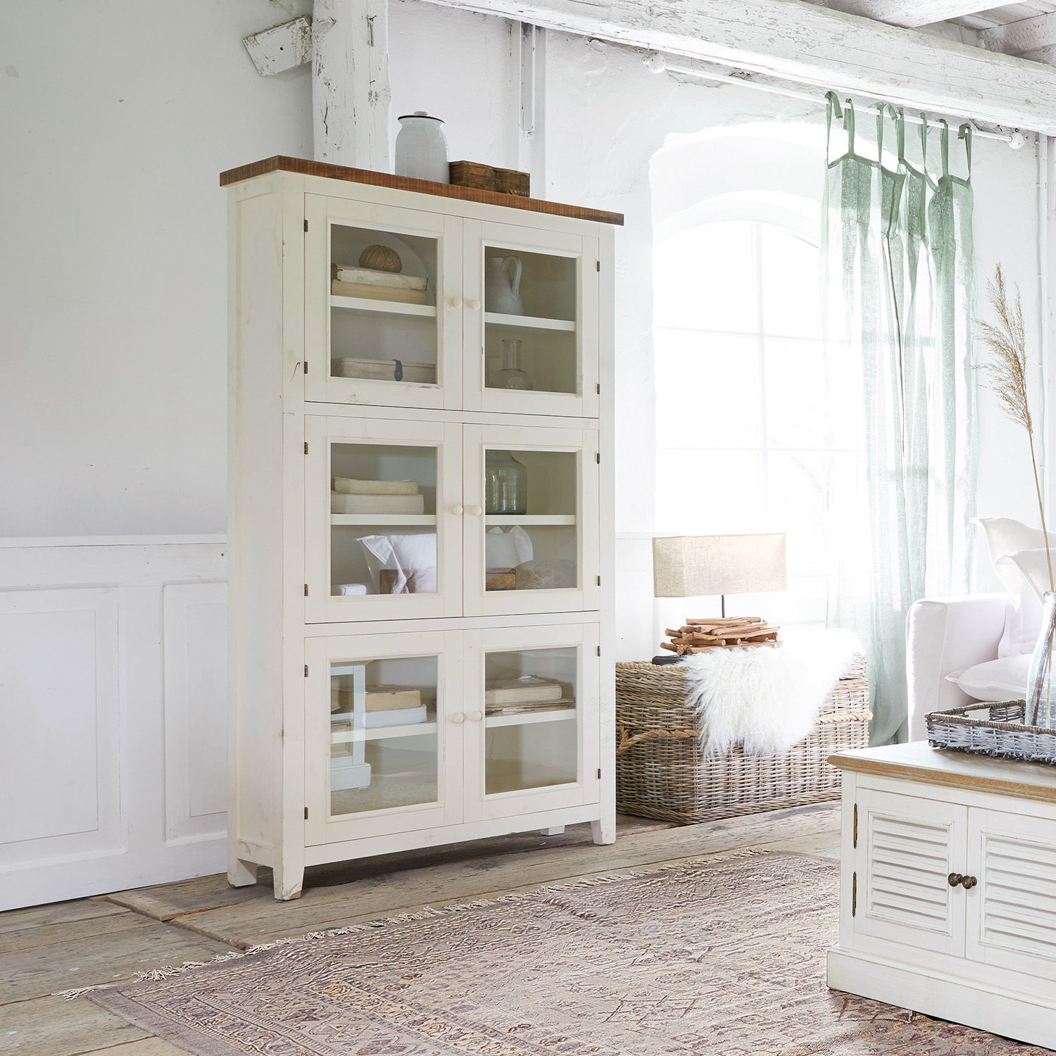 Schrank Yukon Weisse Holzvitrine mit Glastüren im hellen Wohnzimmer mit natürlichem Licht