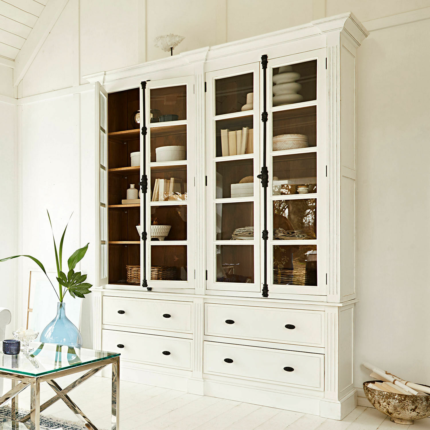 Schrank Laimont Weisse Holzvitrine mit Glastüren und schwarzen Griffen in hellem Raum