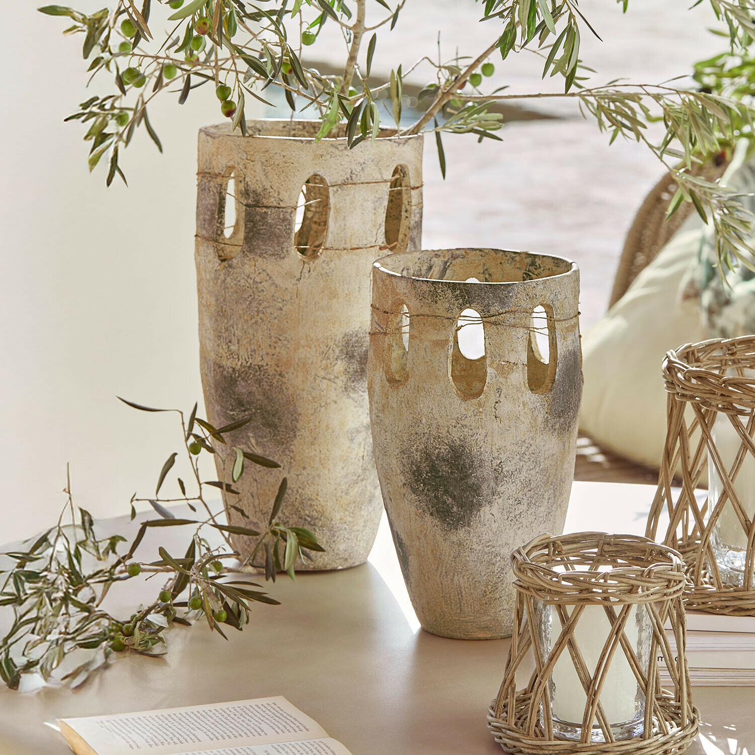 Vase 2er Set Delunas Zwei dekorative Steinvasen in Beige-Grau mit Öffnungen und Olivenzweigen auf einem Tisch
