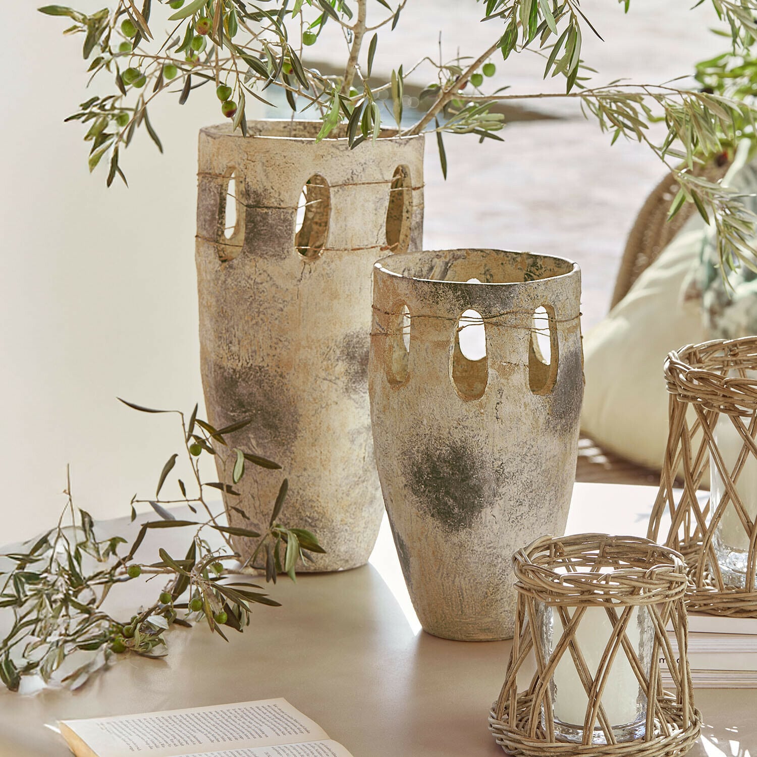 Vase 2er Set Delunas Zwei dekorative Steinvasen in Beige-Grau mit Öffnungen und Olivenzweigen auf einem Tisch