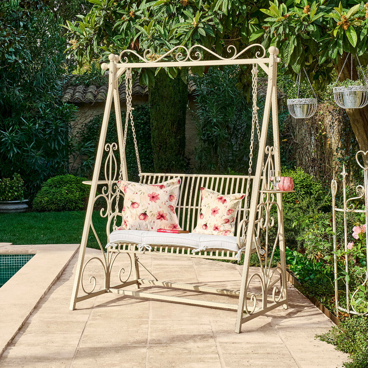 Metall-Gartenschaukel in Creme mit Blumenmustern auf Kissen auf Terrasse neben Pool