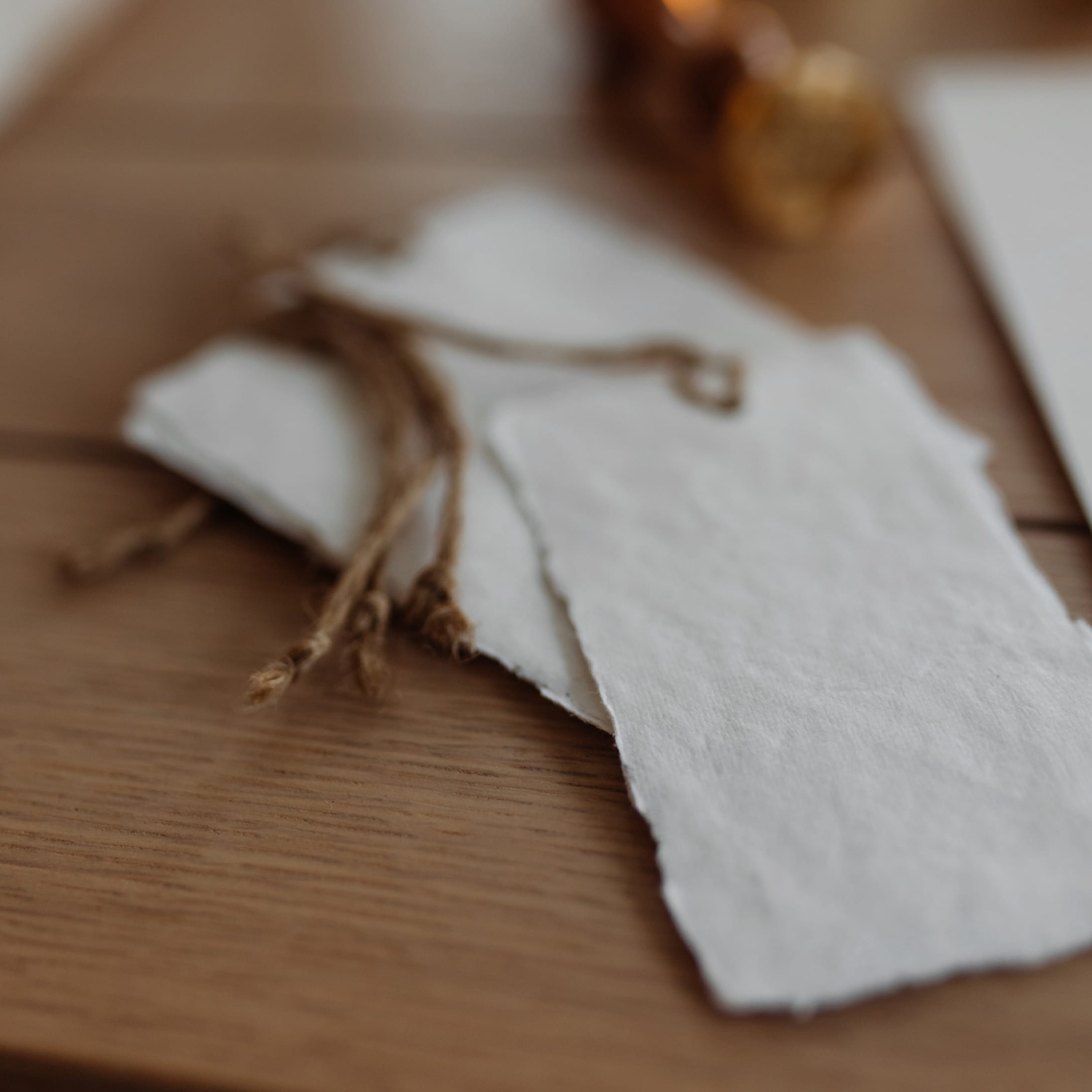 Weisse Papieranhänger mit Naturkordel zum Verpacken von Geschenken auf Holztisch