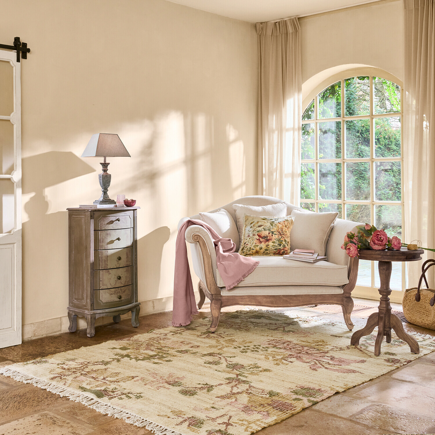 Gemütliches Wohnzimmer mit beigem Sofa, Holztisch, Lampe und floral gemustertem Teppich