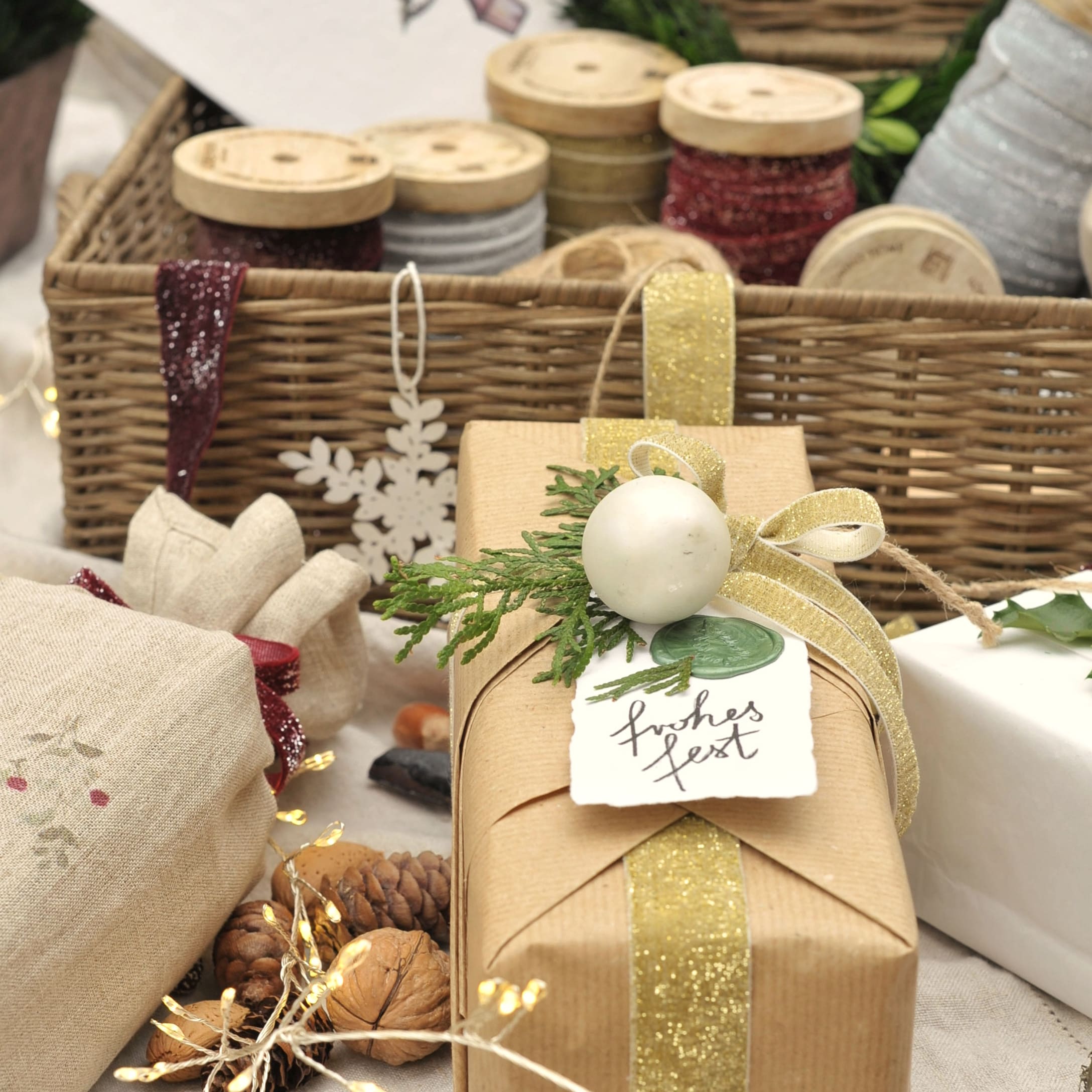 Geschenk in braunem Packpapier mit goldenem Band und grüner Weihnachtsdekoration verpackt