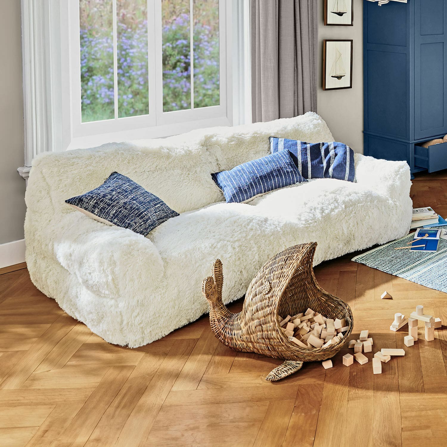 Kindersofa Cerveteri Weisses, flauschiges Sofa mit blauen Kissen in hellem Wohnzimmer mit Holzparkett