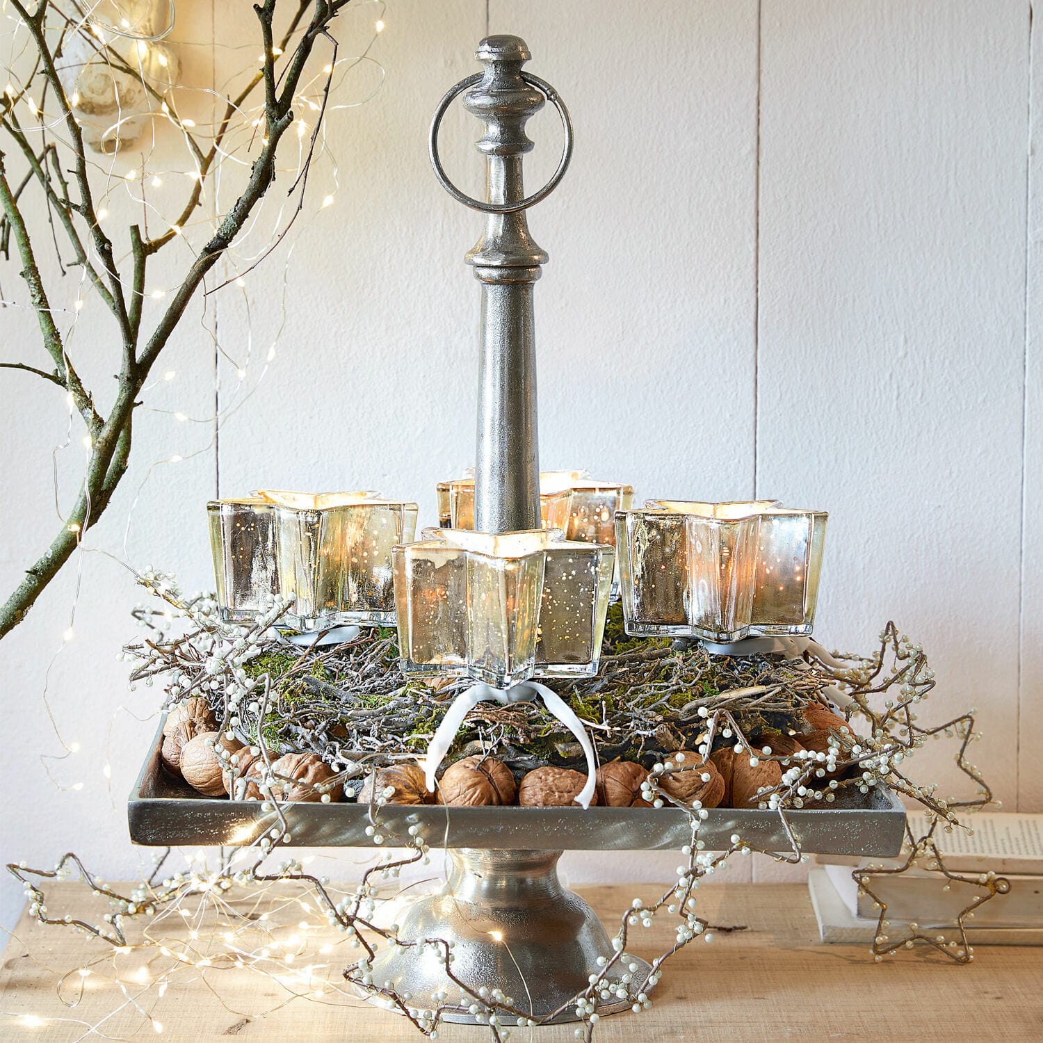 Metall-Kerzenhalter mit vier sternförmigen Glaslichtern, dekoriert mit Nüssen und Zweigen