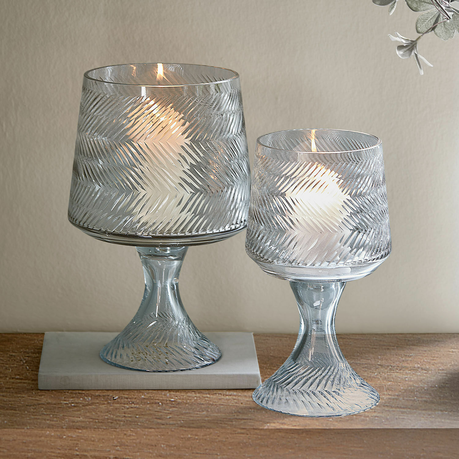 Windlicht 2er Set Lynettes Zwei transparente Glaswindlichter mit Reliefmuster und weissen Kerzen auf Holztisch