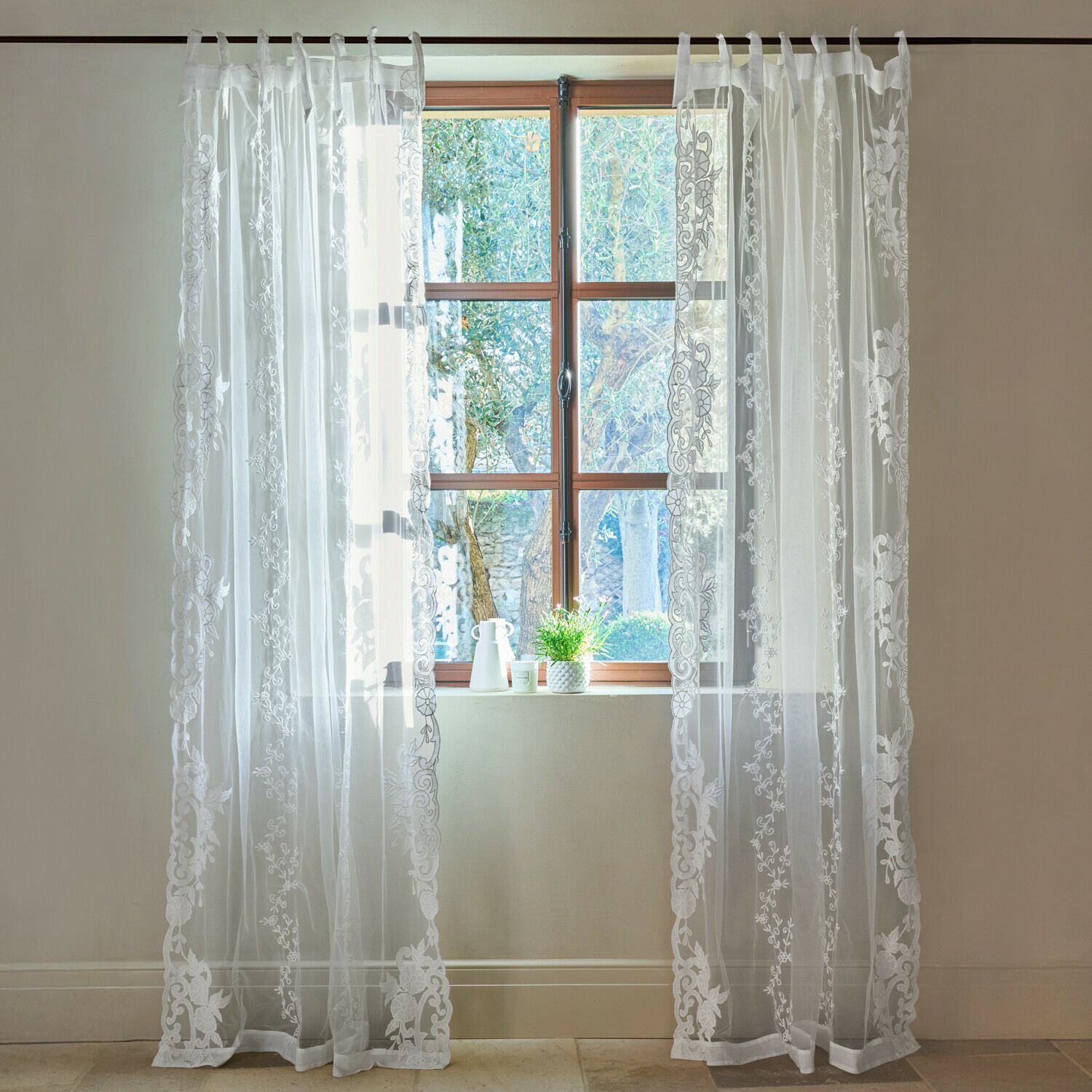 Transparenter weisser Vorhang mit besticktem Blumenmuster am Fenster, elegante Raumdekoration