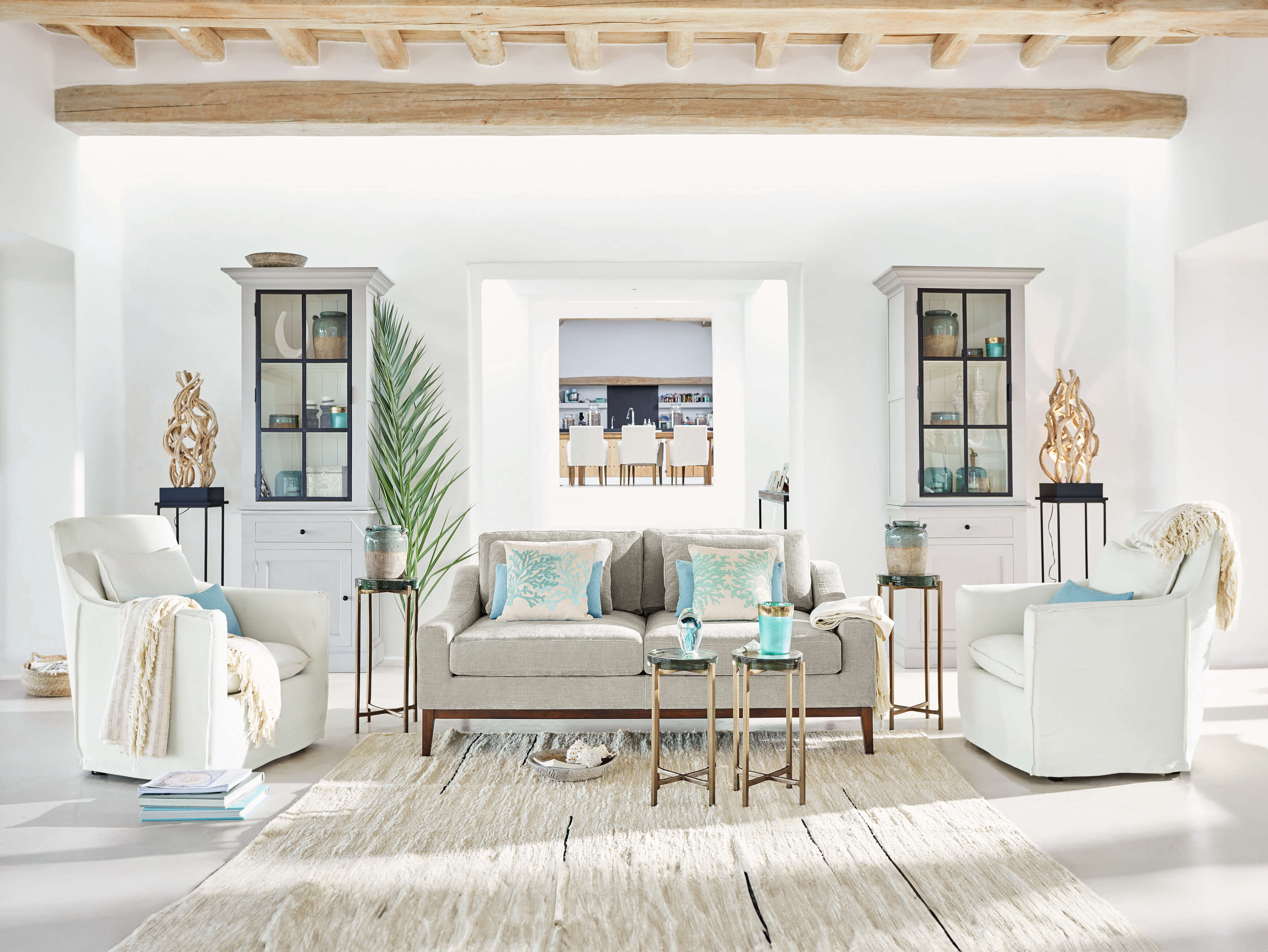 Helles Wohnzimmer mit grauem Sofa, weissen Sesseln und maritimen Dekorationen aus Naturholz