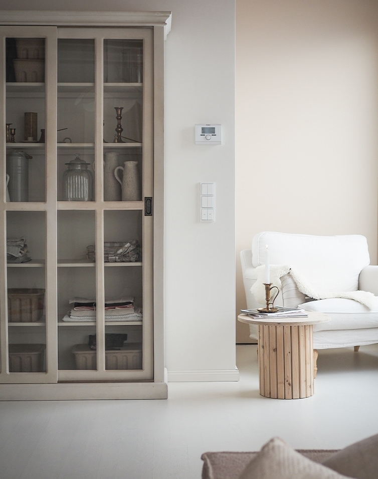 Helles Wohnzimmer mit weissem Sofa, Holztisch und Vitrinenschrank im skandinavischen Stil