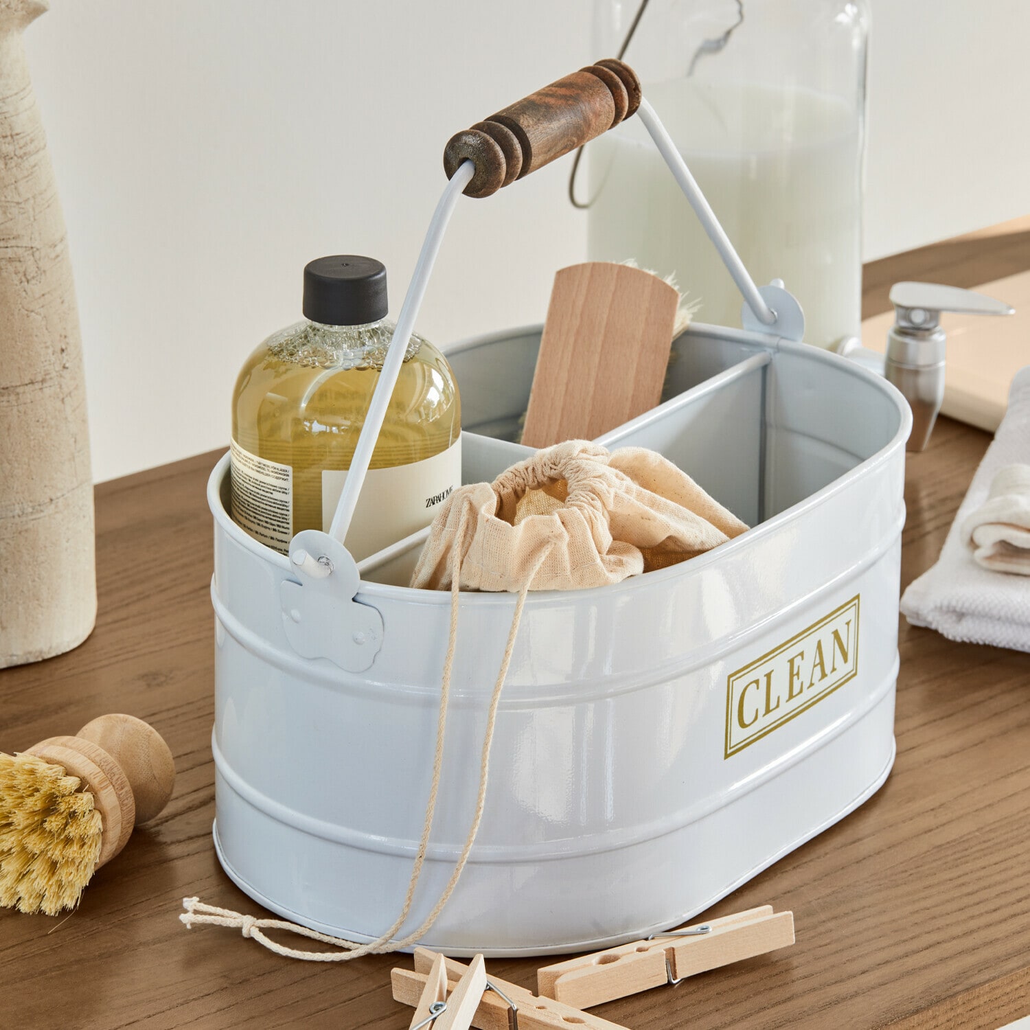 Weisse Metall-Organizer mit Holzgriff und Aufschrift CLEAN, gefüllt mit Reinigungsutensilien