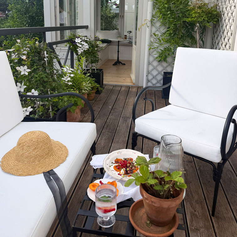 Terrasse mit weissen Metallstühlen, Holzboden und Topfpflanzen für gemütlichen Aussenbereich