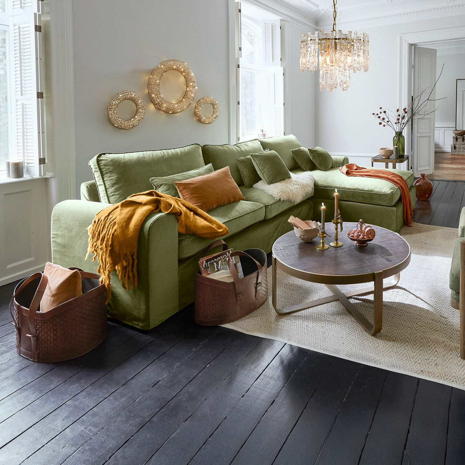 Sofa Seaford Gemütliche grüne Eckcouch aus weichem Stoff im Wohnzimmer mit dunklem Holzboden und dekorativer Beleuchtung
