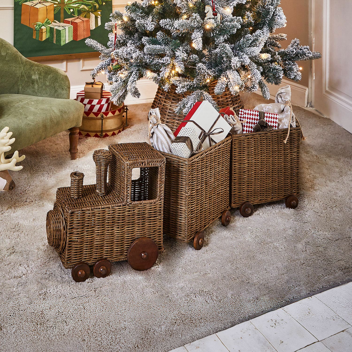 Deko-Zug Kareeva Brauner Dekozug aus Rattan mit Holzrädern, gefüllt mit Weihnachtsgeschenken im Wohnzimmer
