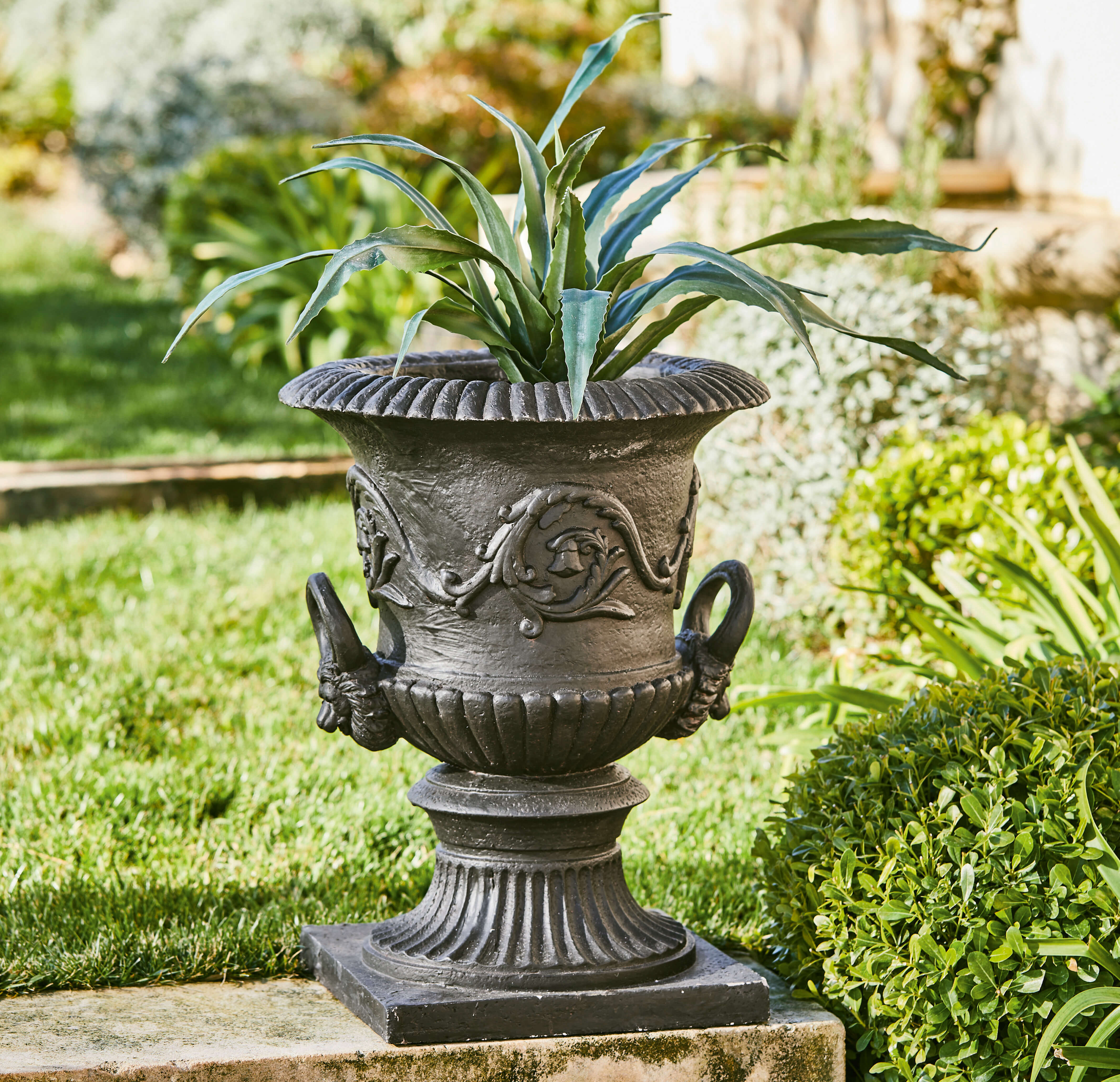 Schwarzer dekorativer Pflanzkübel aus Gusseisen mit Pflanzenmotiv im klassischen Stil im Garten