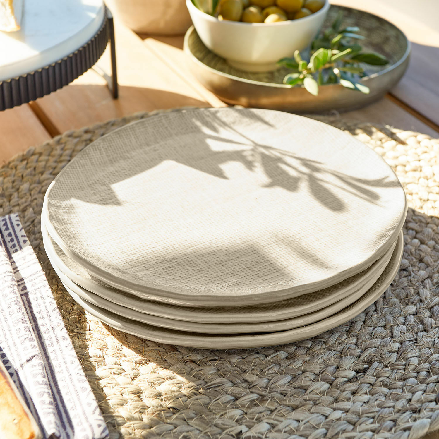 Dessertteller 4er Set Luganville Set aus cremefarbenen, strukturierten Keramiktellern auf geflochtenem Platzset aus Holz