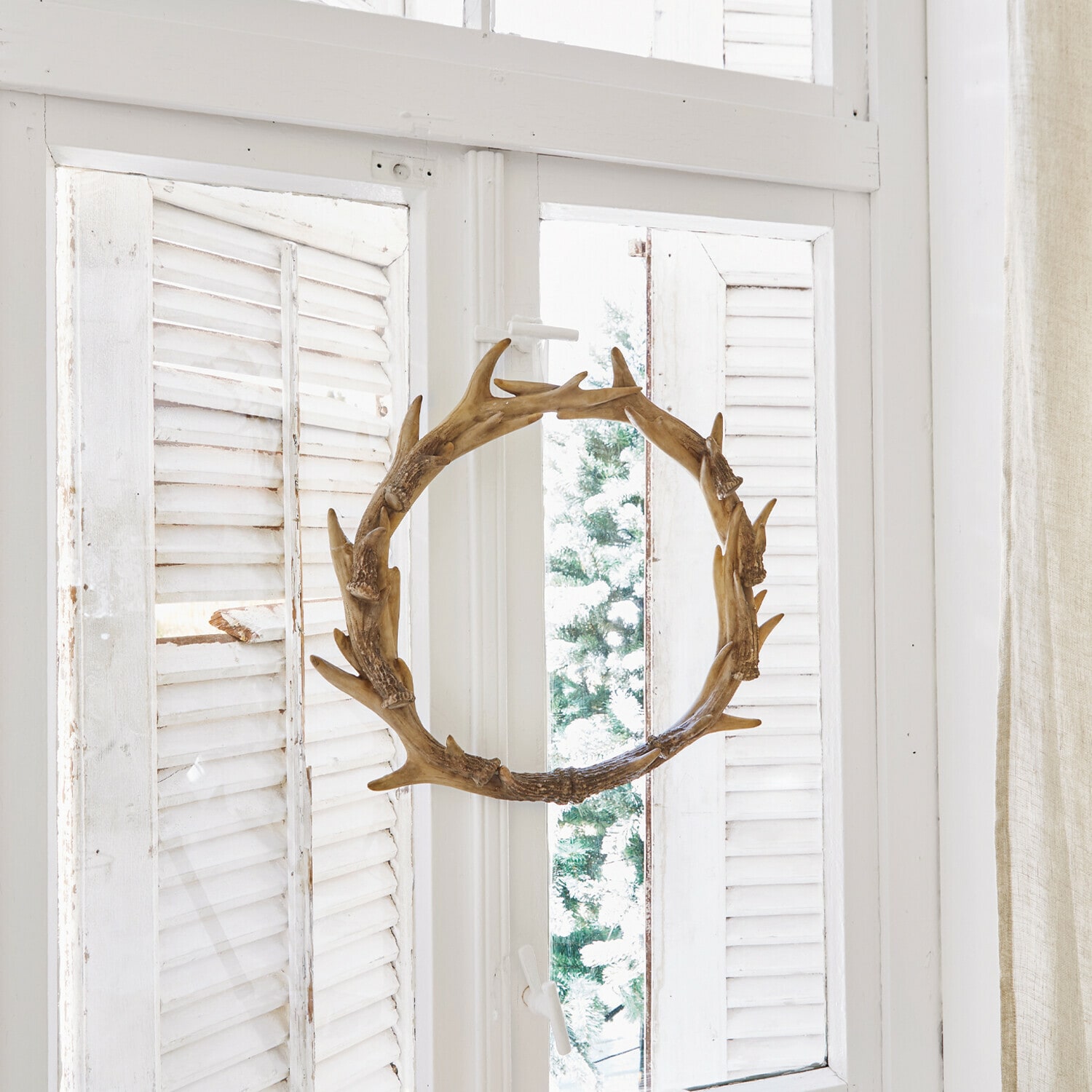 Kranz Marcelle Dekorativer Holzkranz in Geweihform am weissen Fenster mit Kerzen und Tannenzapfen