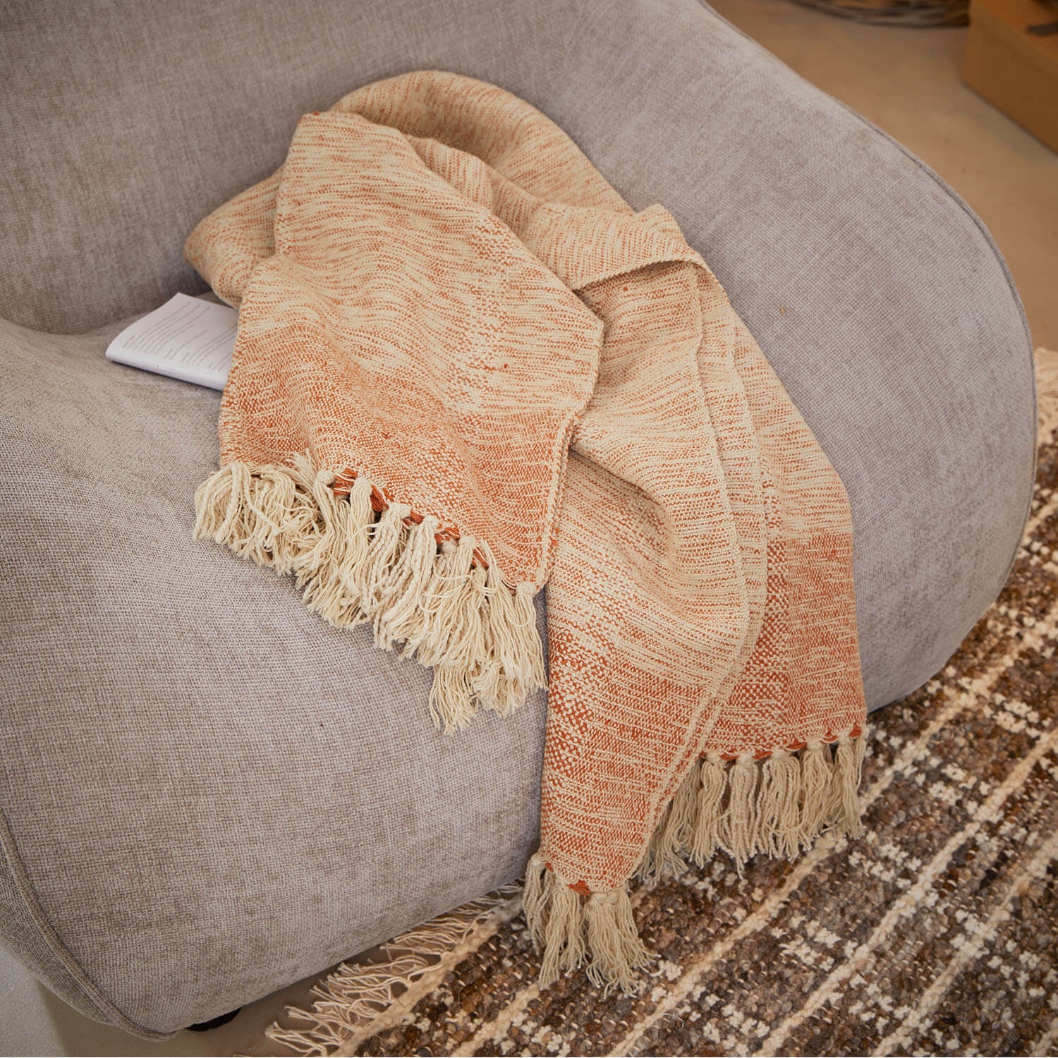 Beige-orangefarbige Decke mit Fransen auf grauem Sofa, weiches Material für Wohnraumdekoration