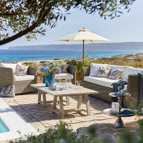 Gartenmöbel-Set aus grauem Technorattan mit cremefarbenen Kissen und Sonnenschirm mit Meerblick