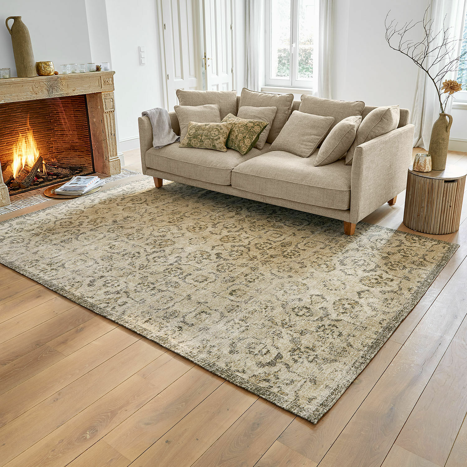 Teppich Calperino Beiger Teppich mit feinem Muster auf Holzboden im Wohnzimmer mit Sofa und Cheminée