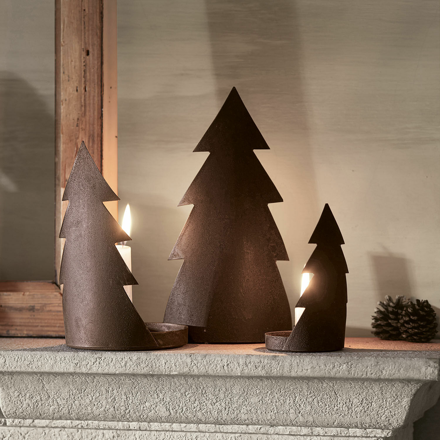 Kerzenständer 3er Set Ageville Drei rostfarbene Metall-Kerzenhalter in Tannenbaumform auf dem Kaminsims, weihnachtliche Dekoration