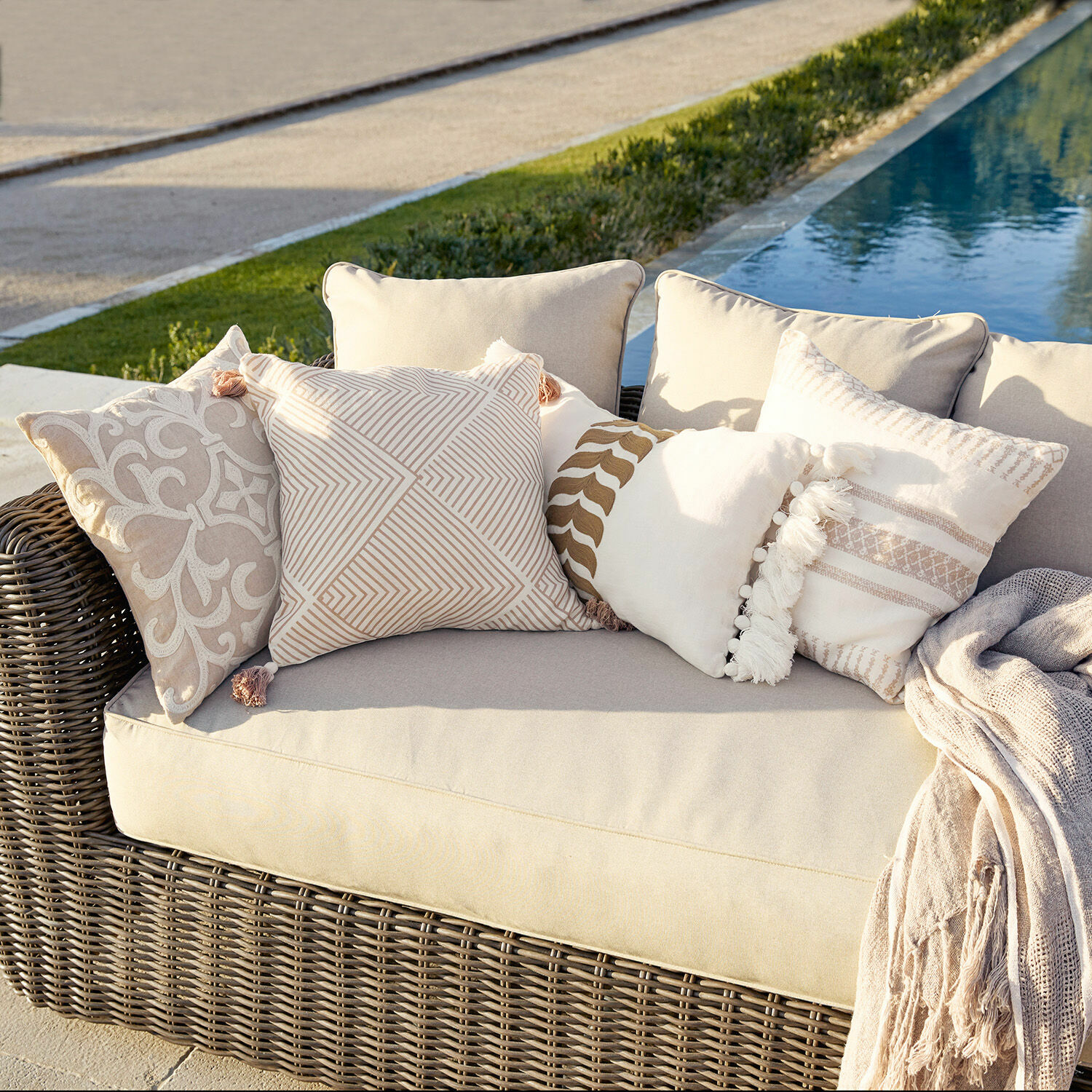 Kissenhülle 4er Set Olette Beiges Rattansofa mit cremefarbenen und beigen Dekokissen draussen am Pool