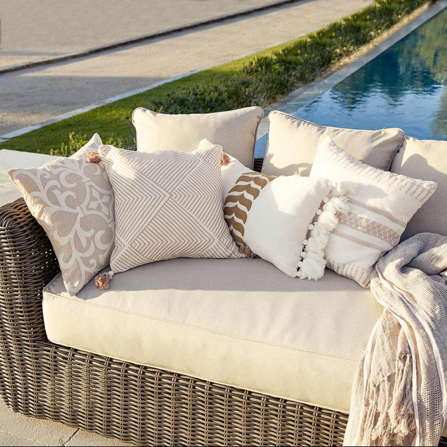 Kissenhülle 4er Set Olette Beiges Rattansofa mit cremefarbenen und beigen Dekokissen draussen am Pool