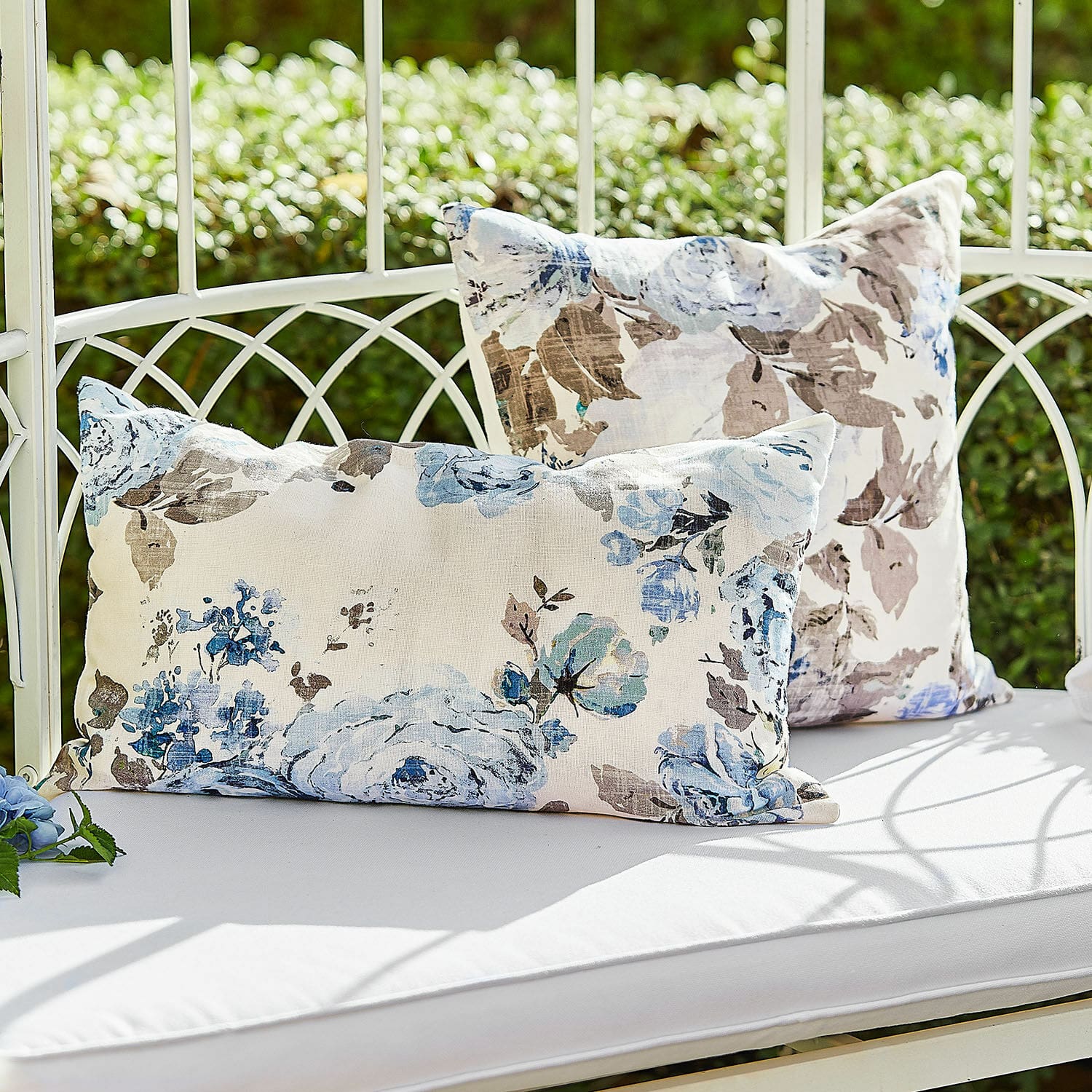 Kissenhülle 2er Set Cloranne Dekorative Baumwollkissen mit blau-braunem Blumenmuster auf weisser Gartenbank im Freien
