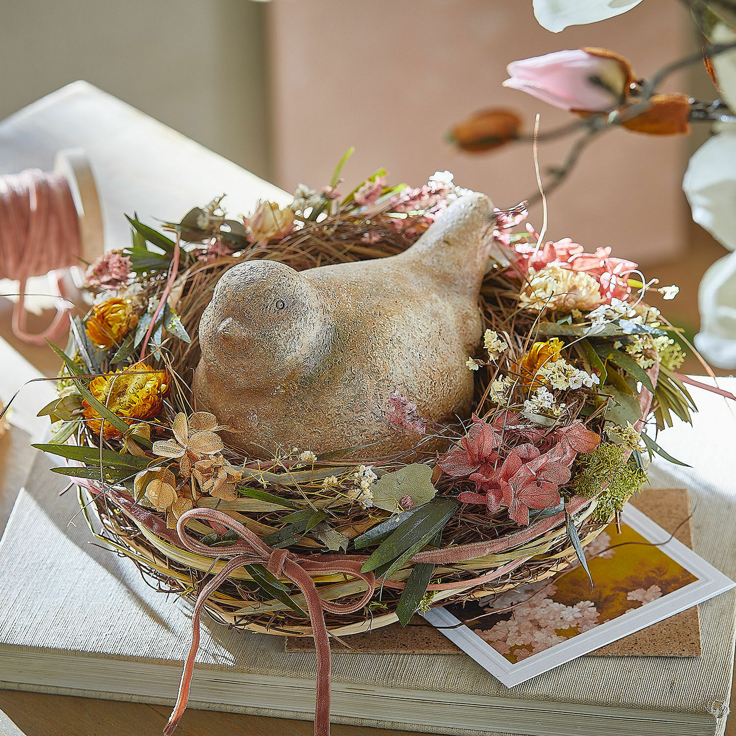 Nest Bravilex Dekorativer Keramikvogel im Nest aus getrockneten Blumen und Blättern auf dem Tisch