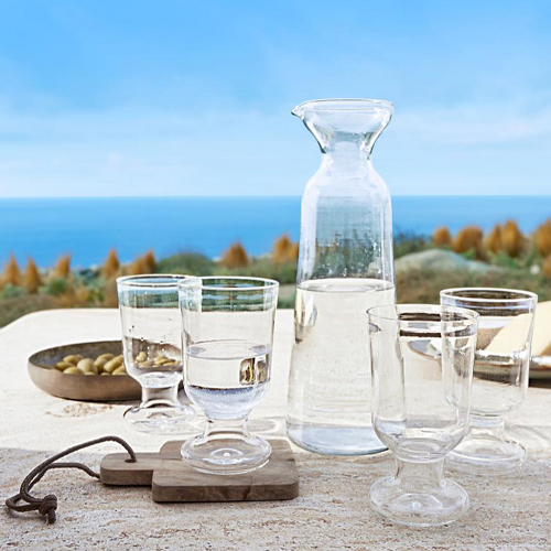 Glaskaraffe und vier durchsichtige Gläser auf dem Tisch mit Meerblick, klares Glas