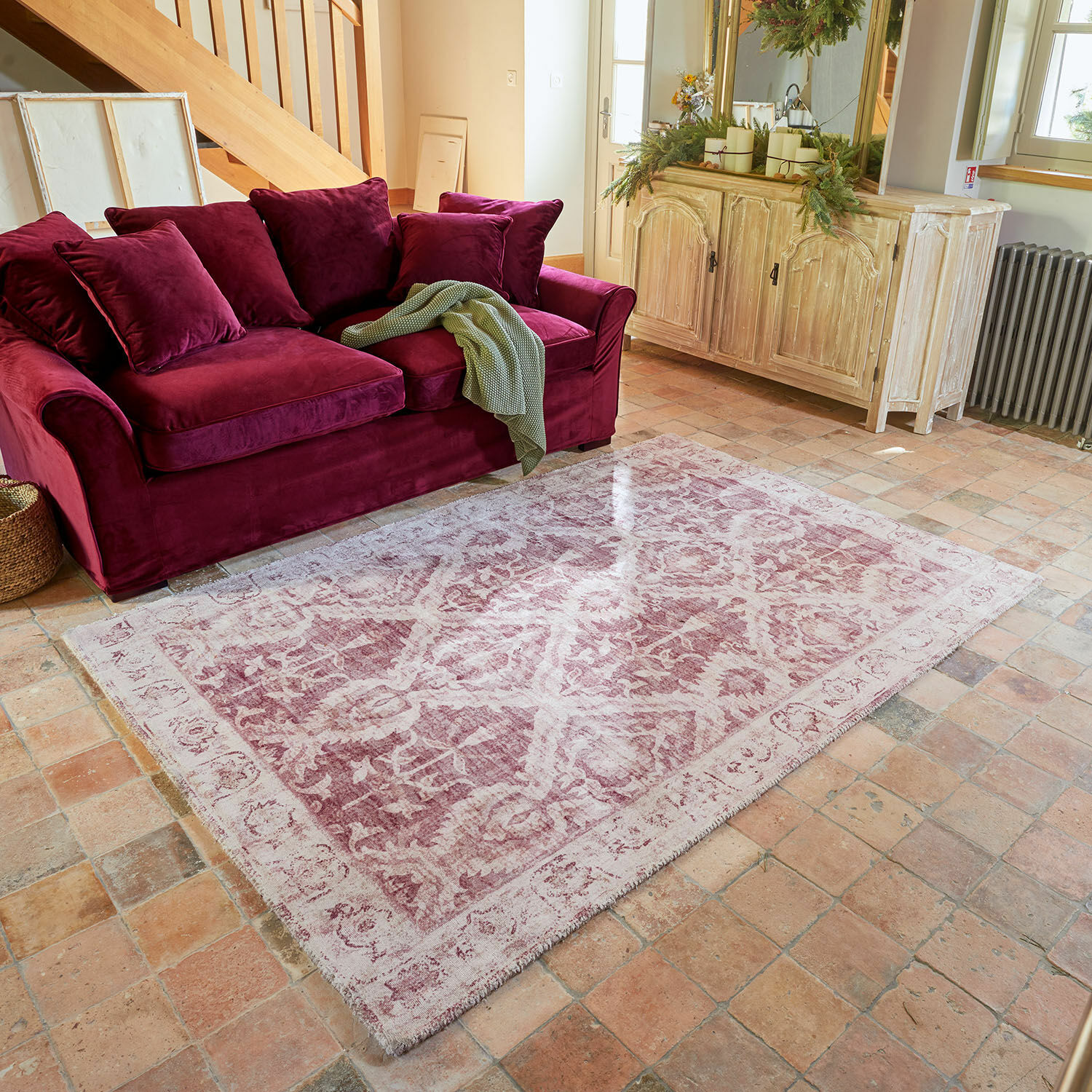 Teppich Mirellis Vintage Teppich in Rosa mit Muster vor bordeauxrotem Samtsofa und hellem Holzsideboard