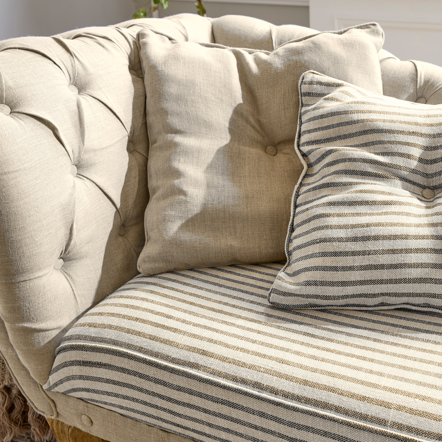 Beige gepolstertes Sofa mit gestreiften und einfarbigen Kissen, weicher Stoff, gemütliches Möbel