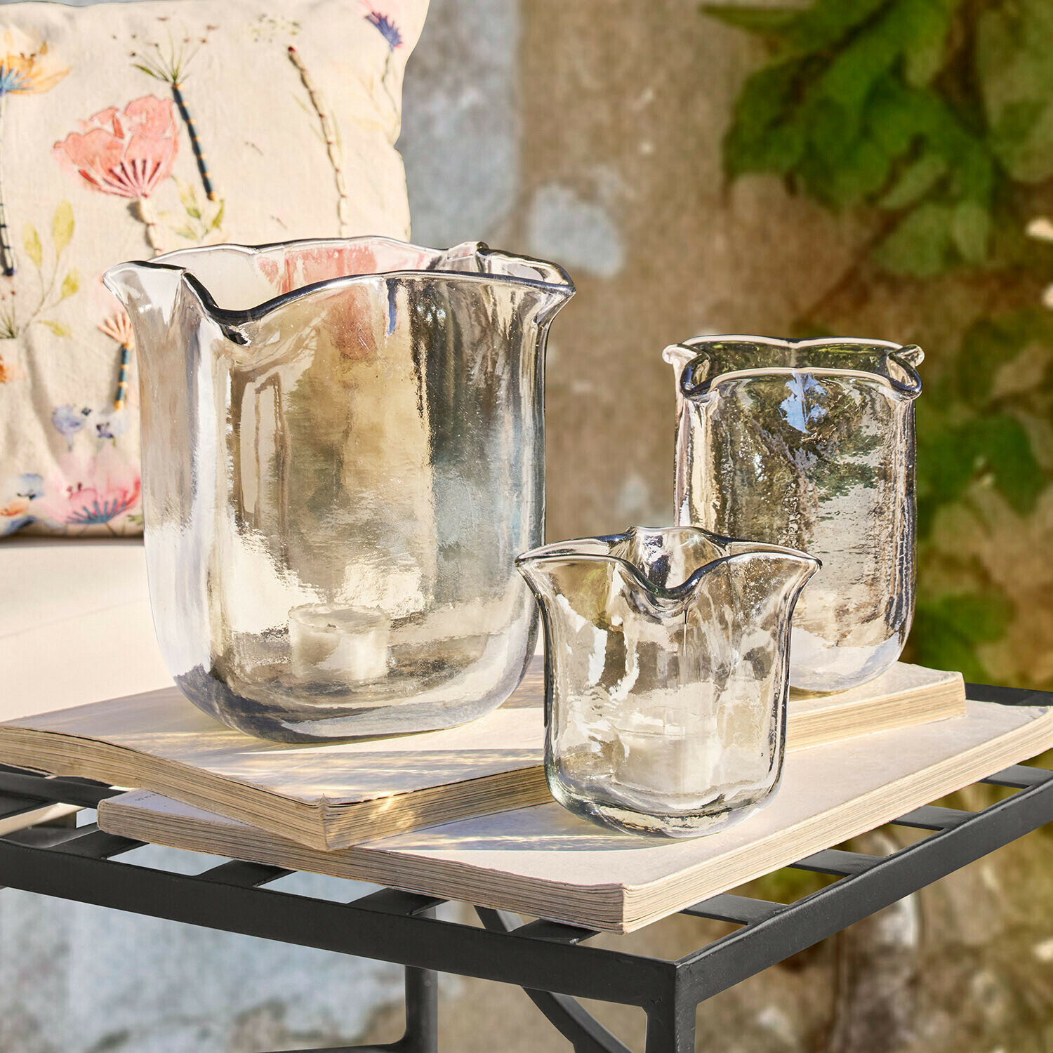 Windlicht 3er Set Ilomiane Set mit drei transparenten Glas-Teelichthaltern mit unregelmässiger Form auf Büchern
