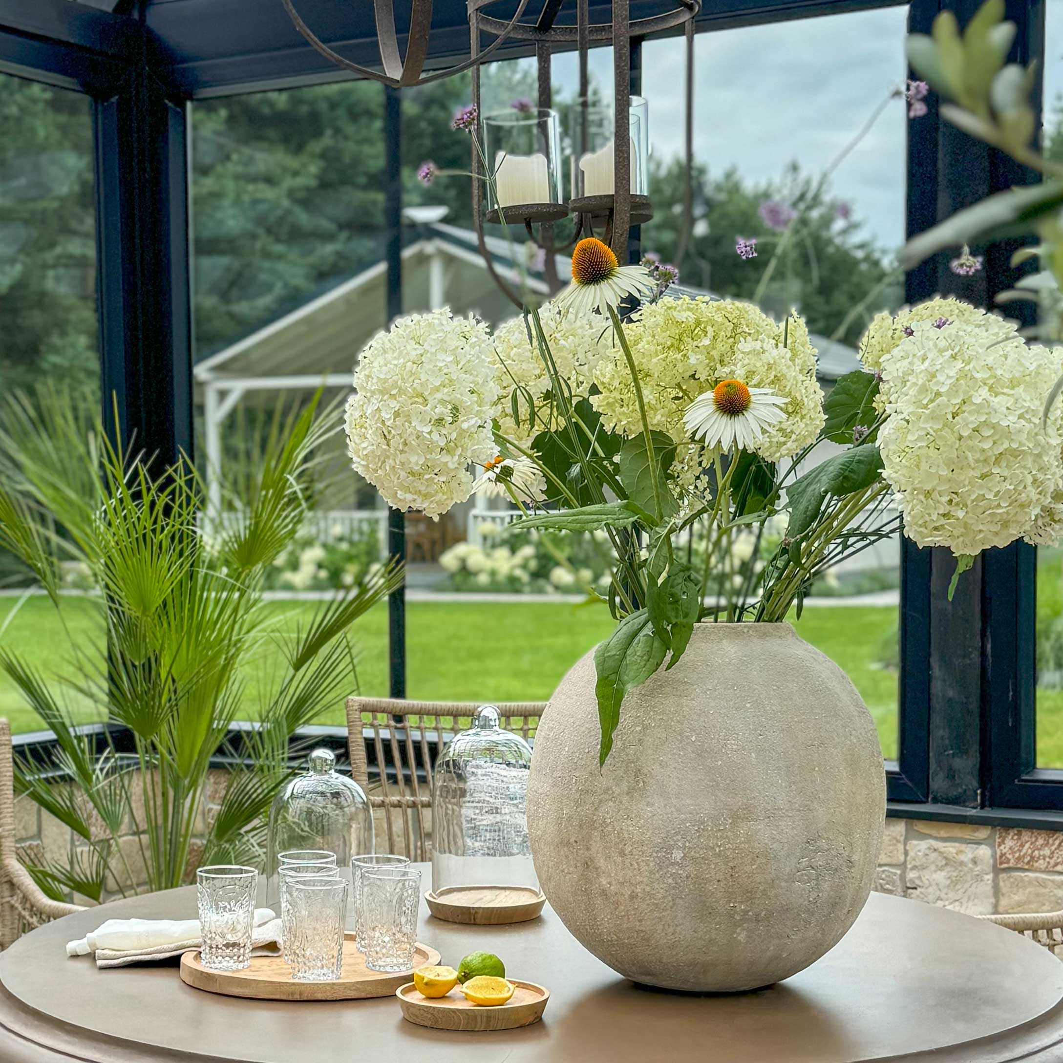 Grosse runde Betonvase mit weissen Blumen auf Gartentisch, Wohn- und Gartenmöbel Dekoration