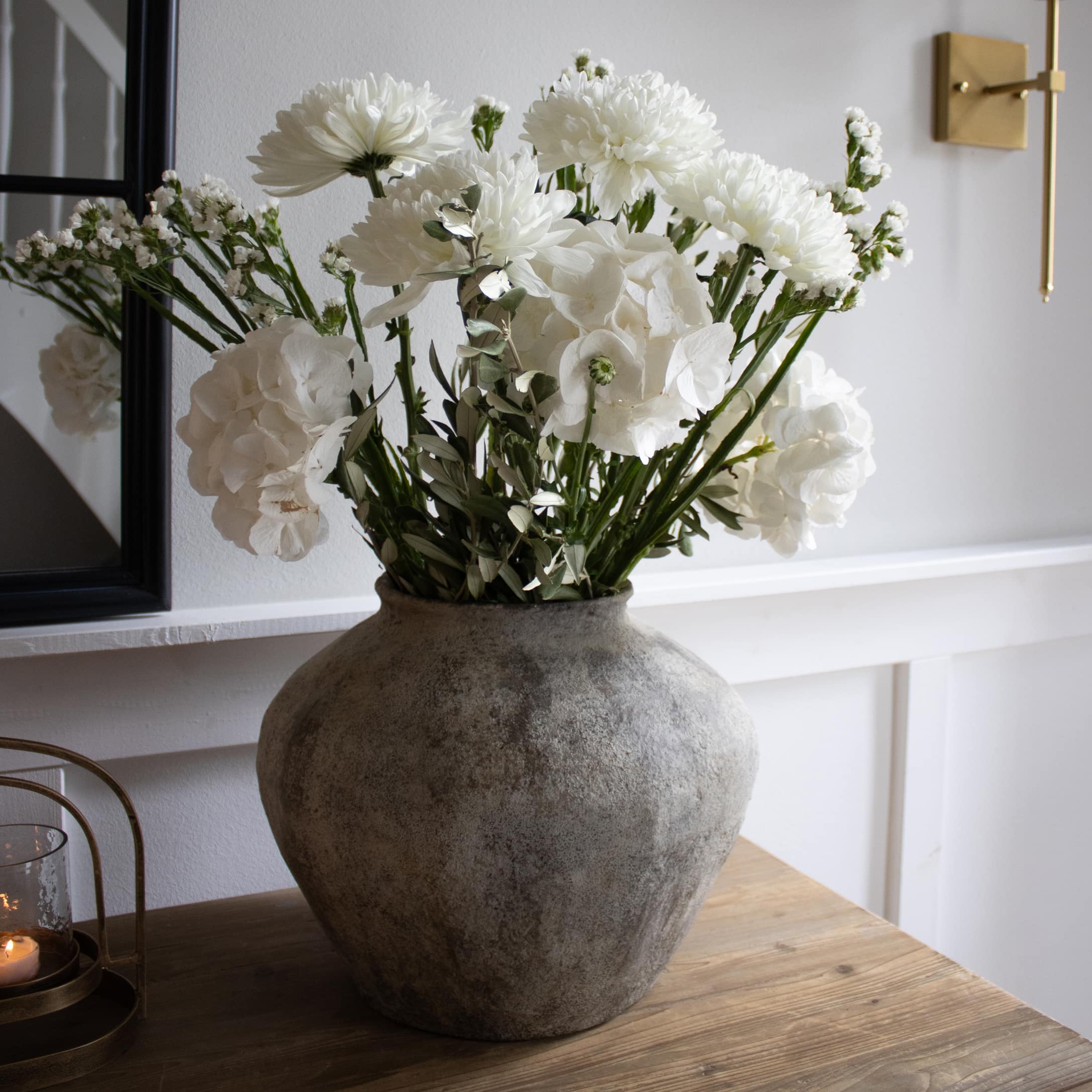 Grosse graue Steinvase mit weissen Blumen auf Holztisch in modernem Interieur