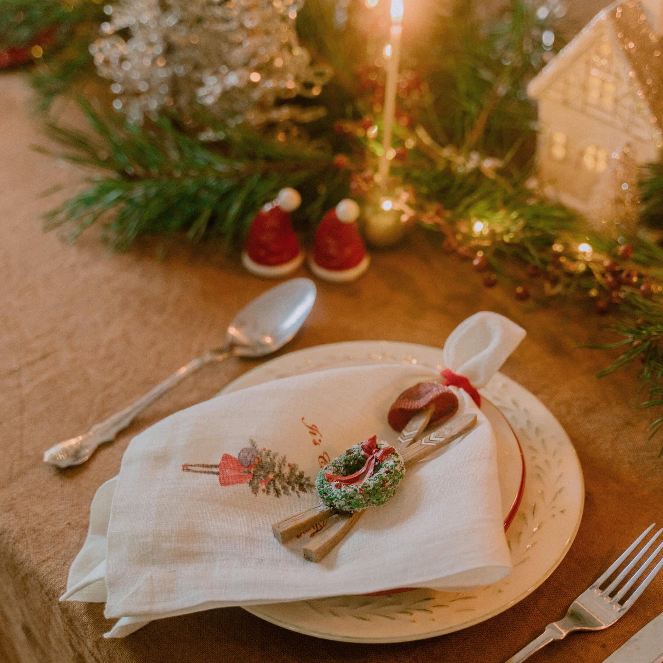Weihnachtliche Tischdekoration mit weisser Leinenserviette und grünem Kranz auf Keramikteller