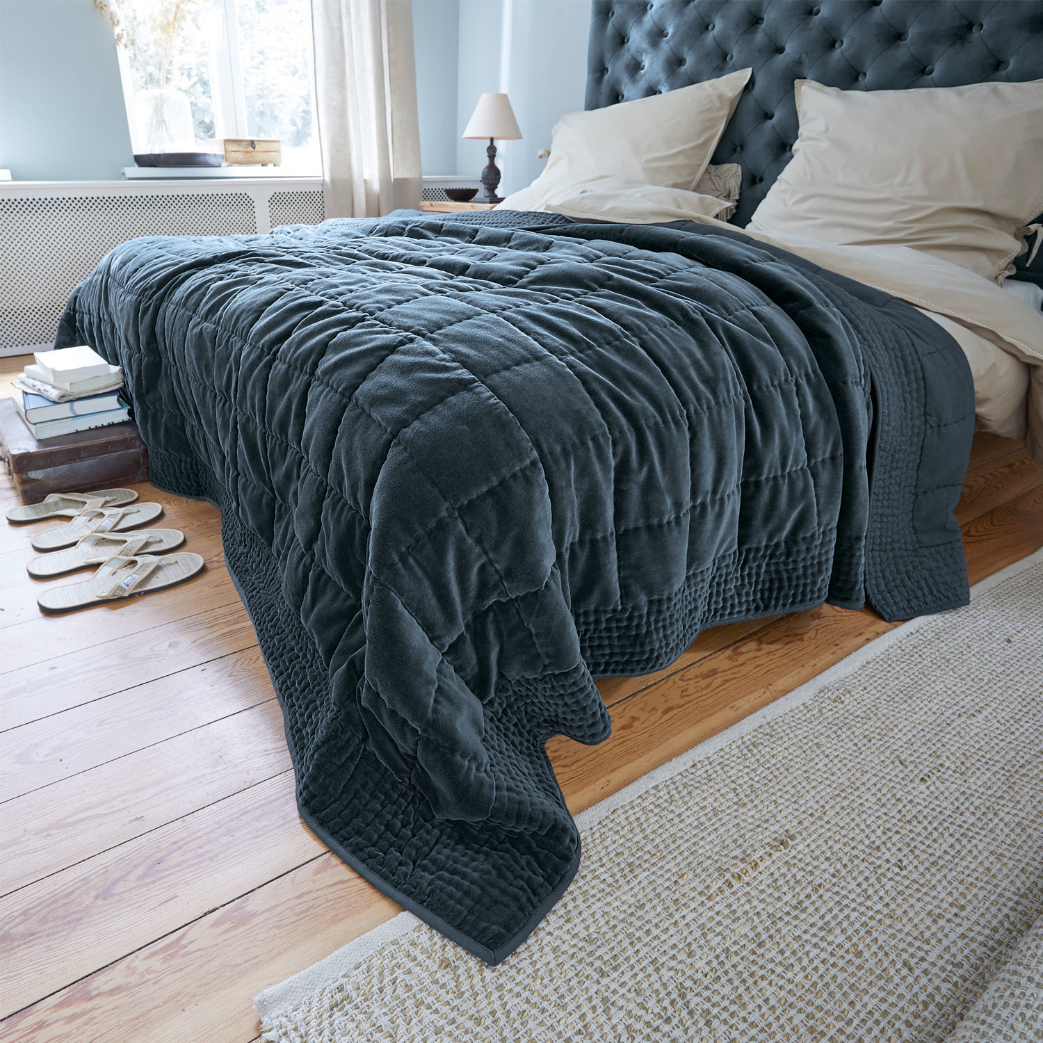 Quilt Arasta Dunkelblaue, gesteppte Kuscheldecke aus weichem Material auf Bett in hellem Schlafzimmer mit Holzboden