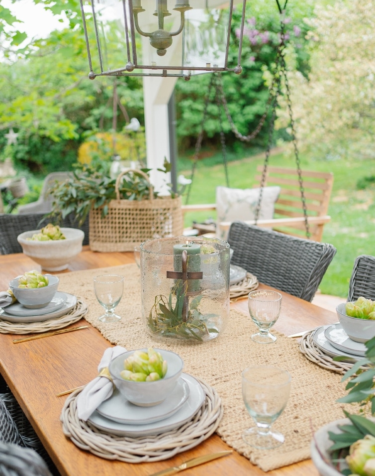 Gartentisch aus Naturholz mit geflochtenen Platzsets und Kerzendekoration in Glasvase